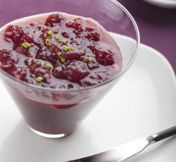 Glass dish of Kicked-Up Cranberry Sauce topped with green herbs