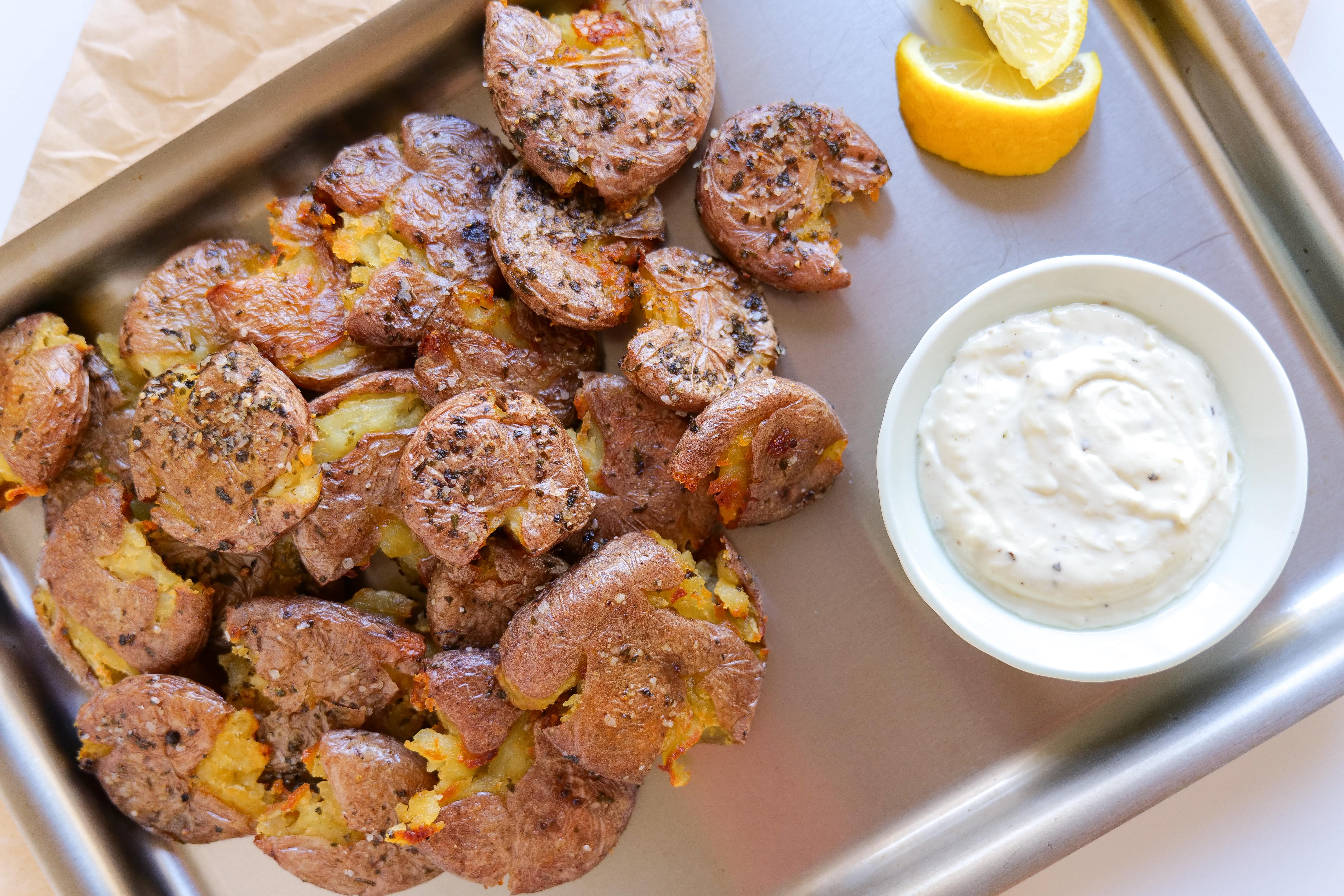 Crispy smash potatoes served with garlic aioli sauce and a lemon wedge