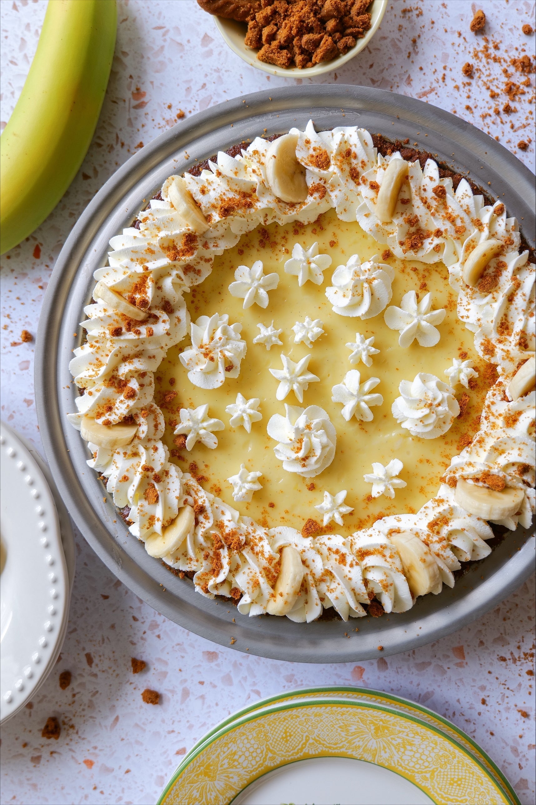 Banana cream pie topped with whipped cream, banana slices, and crushed Biscoff cookies