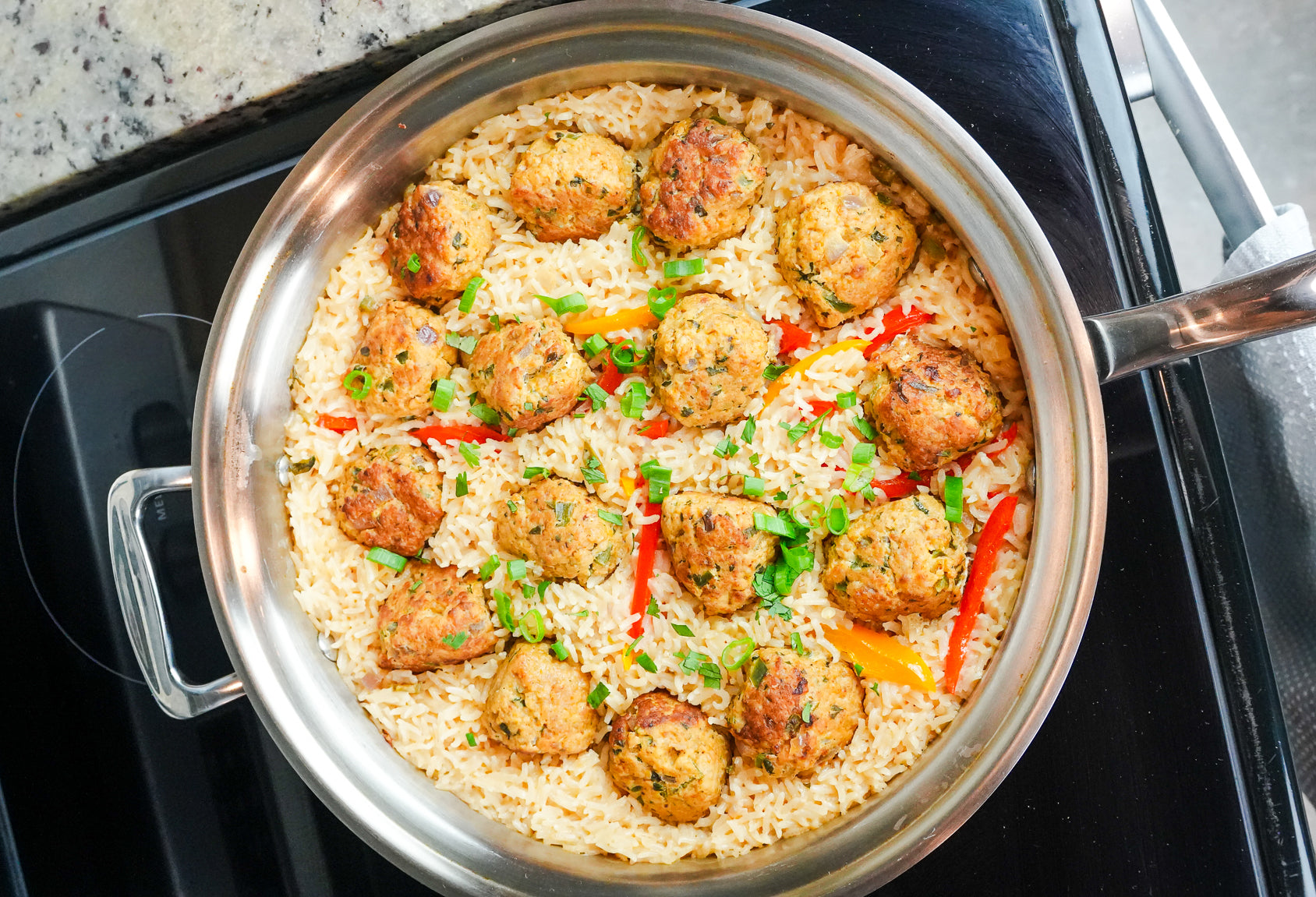 One-pan cilantro chicken meatballs on coconut rice in a stainless steel pot on a stovetop