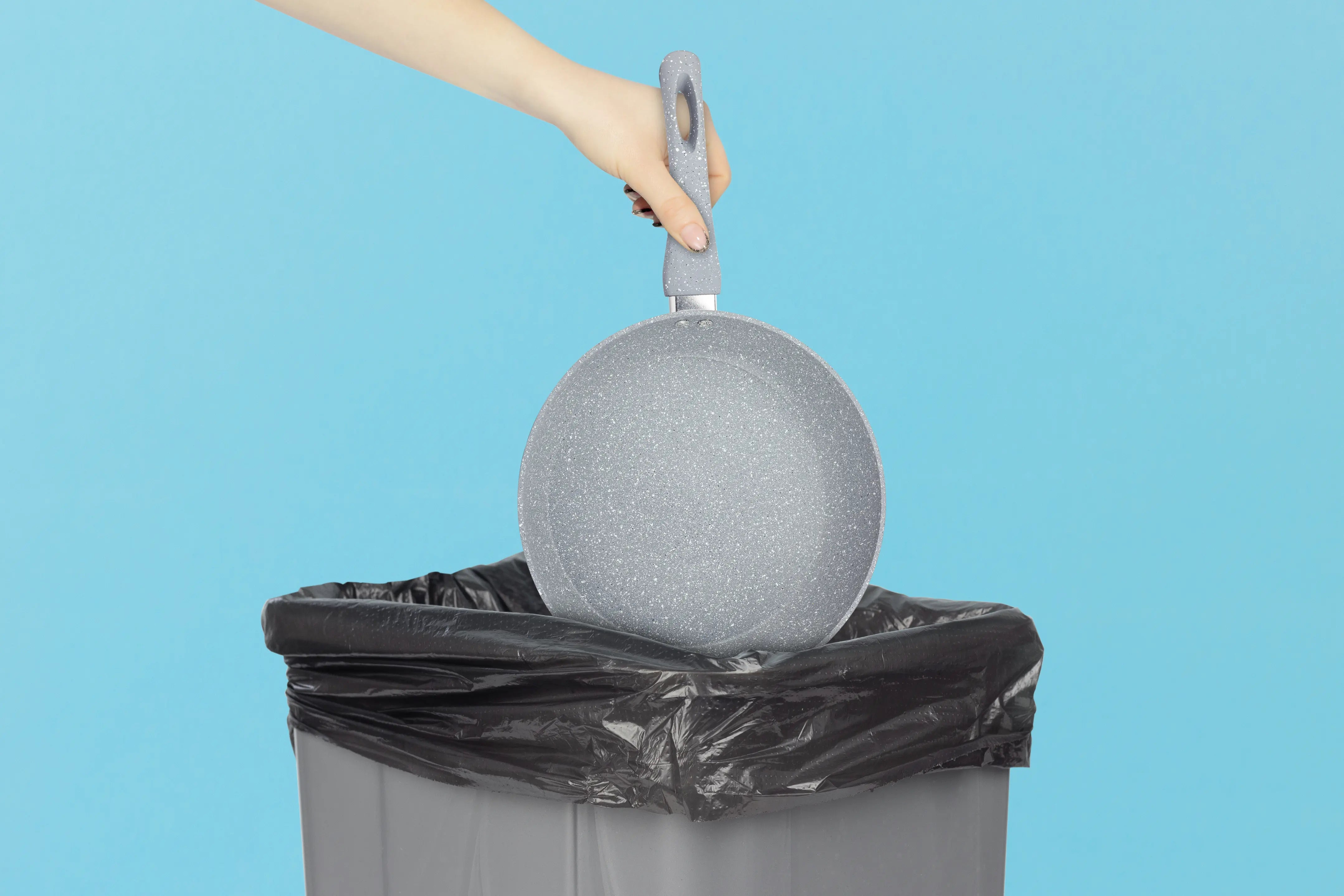 Person throwing away a frying pan in the trash