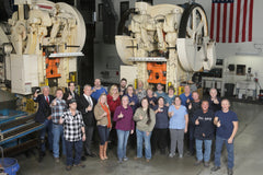 Group photo of 360cookware team in manufacturing facility with machinery in background