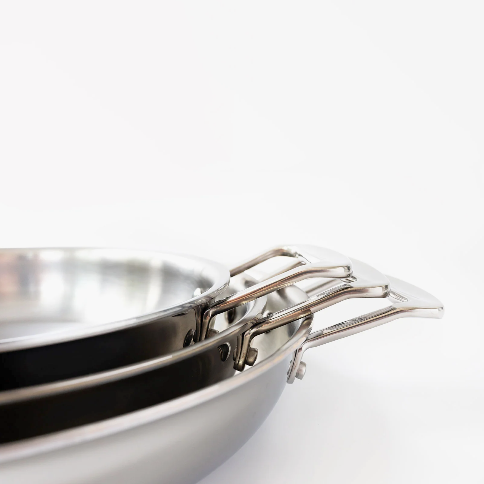 Stacked short-handled fry pans showcasing surgical-grade stainless steel construction.