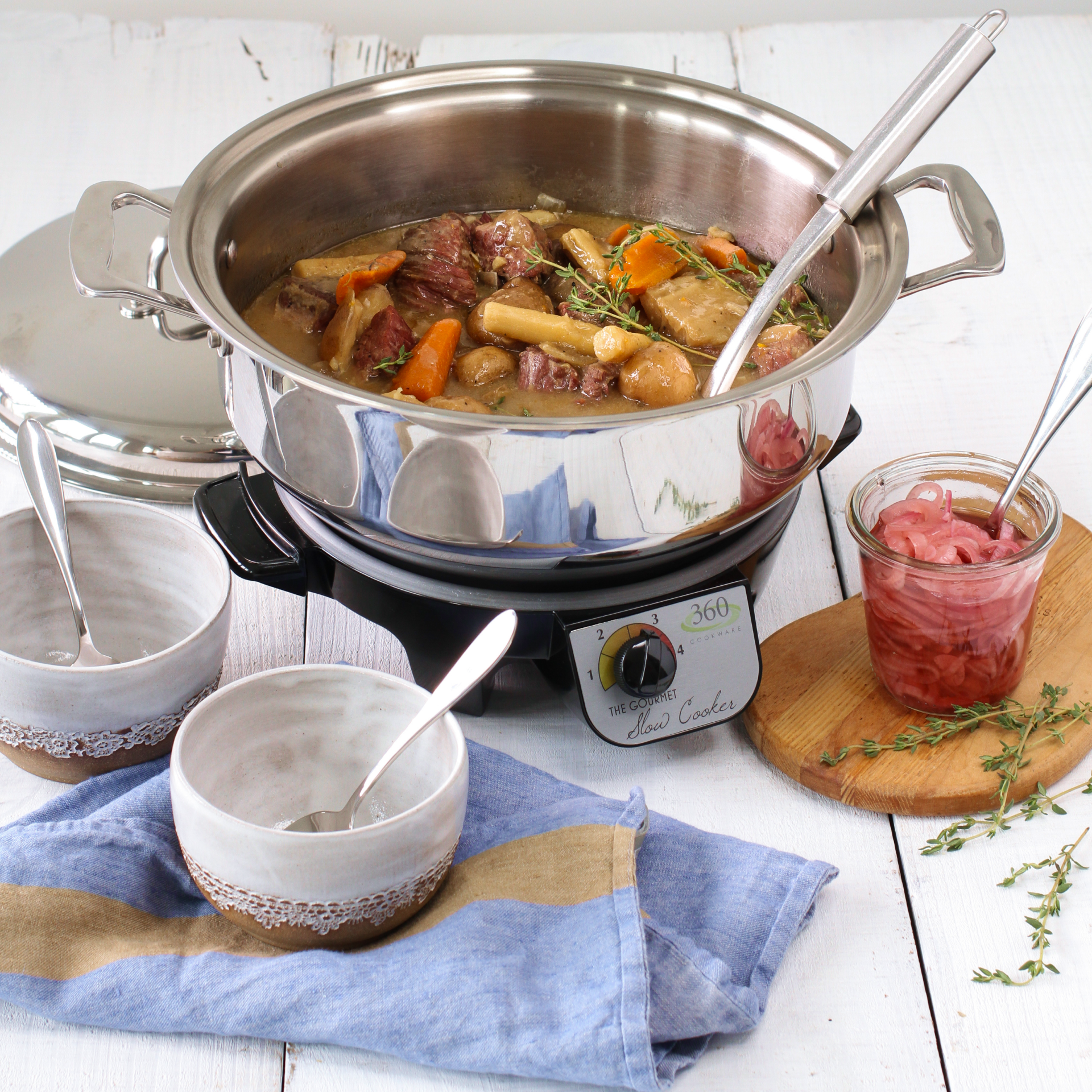 A 6-quart slow cooker with a stew of meat and vegetables, accompanied by bowls and utensils.