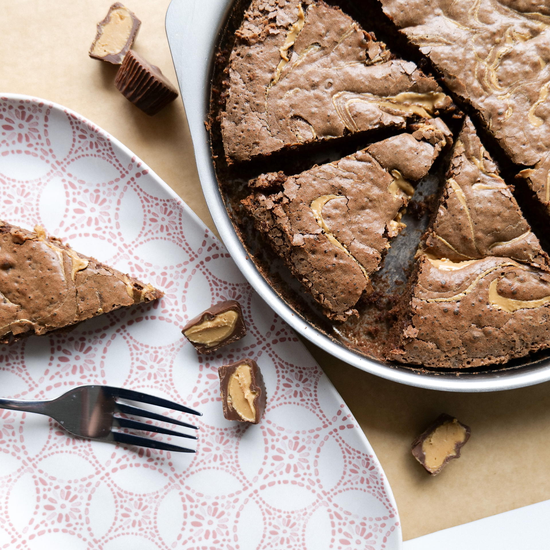 Sliced brownie with peanut butter cups on a decorative plate and fork