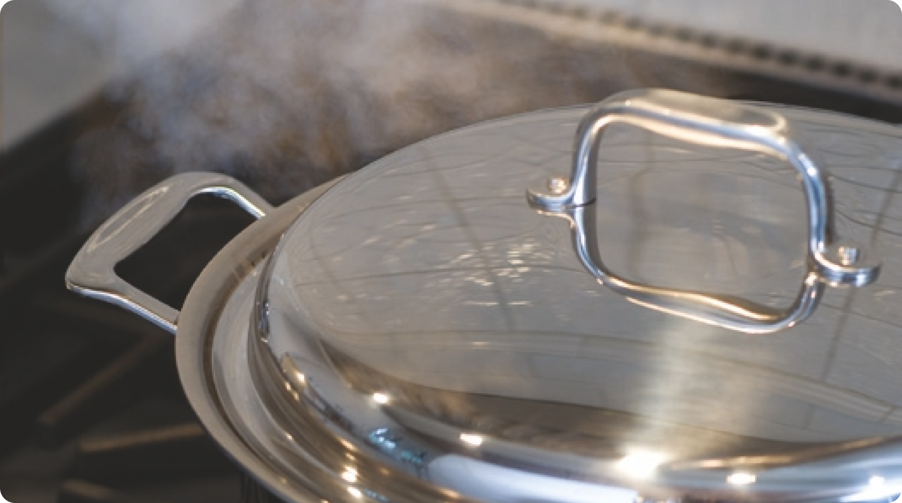 A stainless steel pot with a lid, steam rising, indicating the formation of a Vapor Seal.