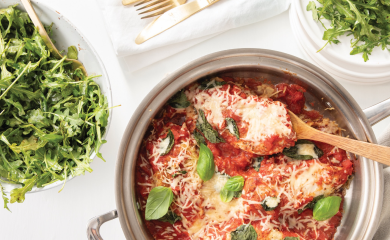 Chicken Parmesan with side salads on a white table