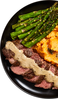 Plate of steak, asparagus, and mashed potatoes with a side of gravy.