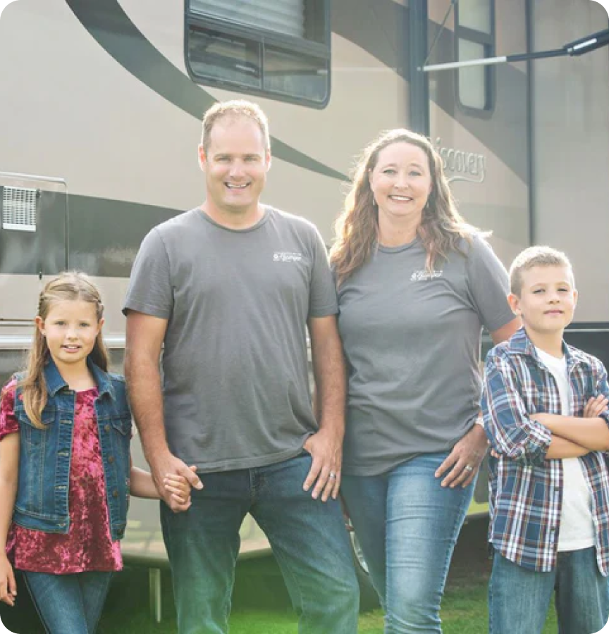 Family portrait of Grateful Glamper influencers standing outside their RV, smiling.