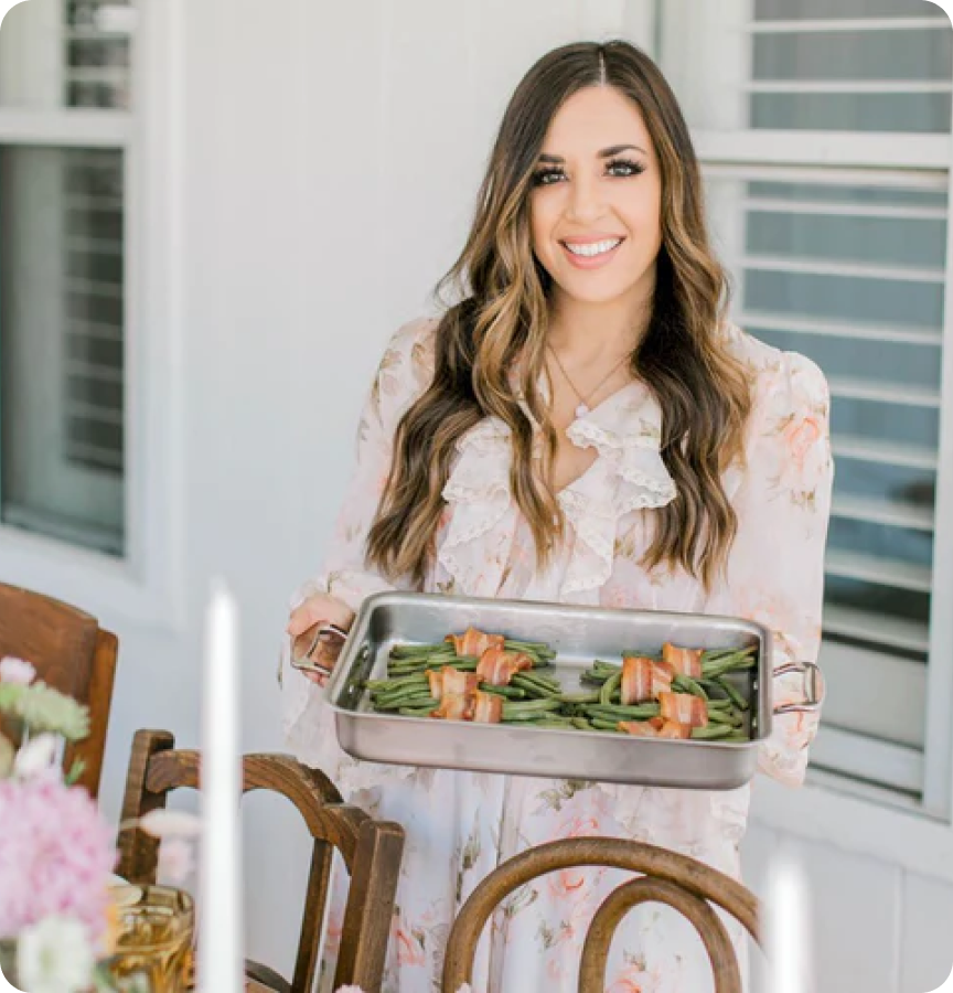 Amanda Warren holding a tray of green beans wrapped in bacon at a beautifully set table
