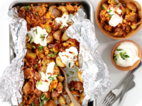 A tray of roasted chicken and potatoes topped with sour cream and green onions.