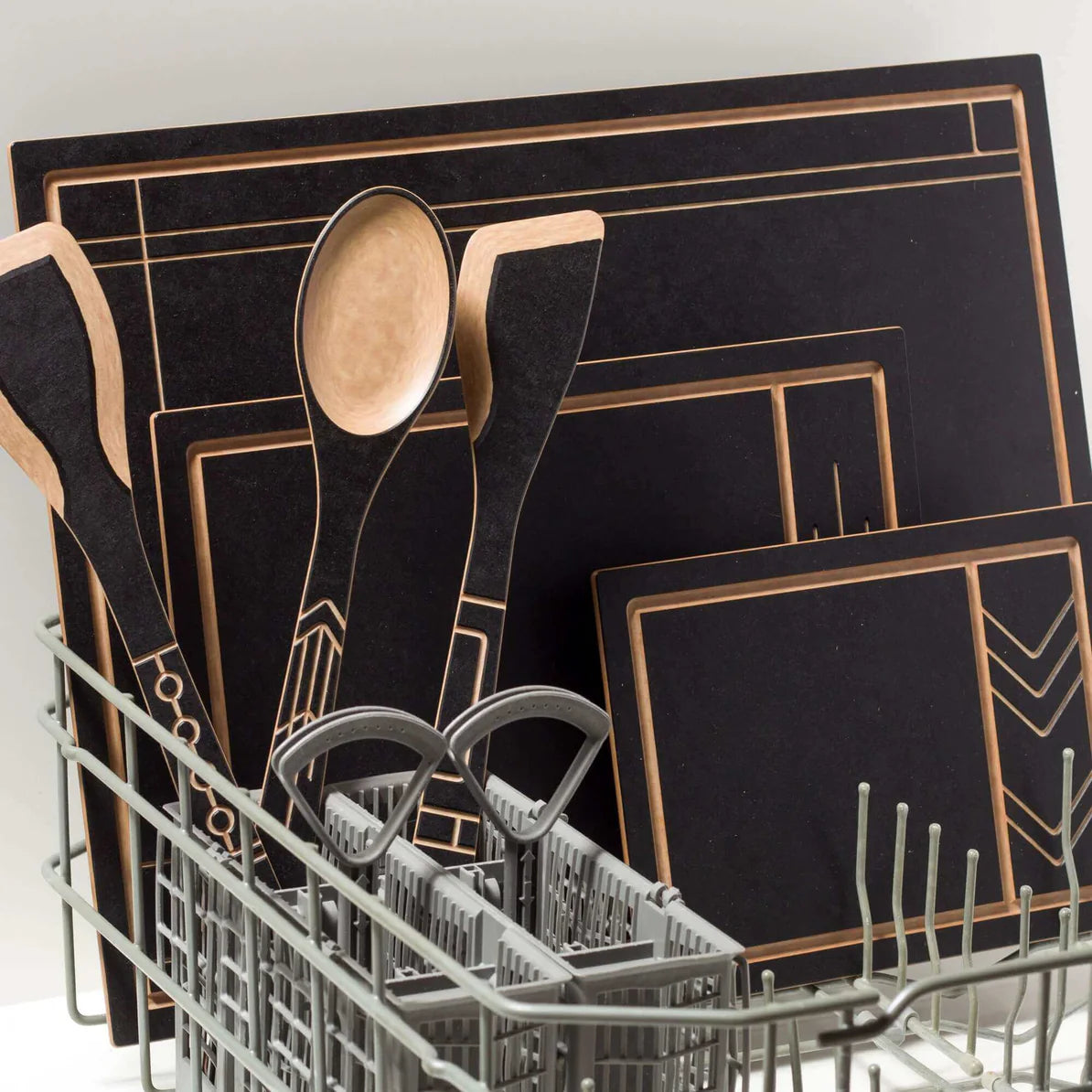 A collection of kitchen utensils and cutting boards in a dishwasher rack.