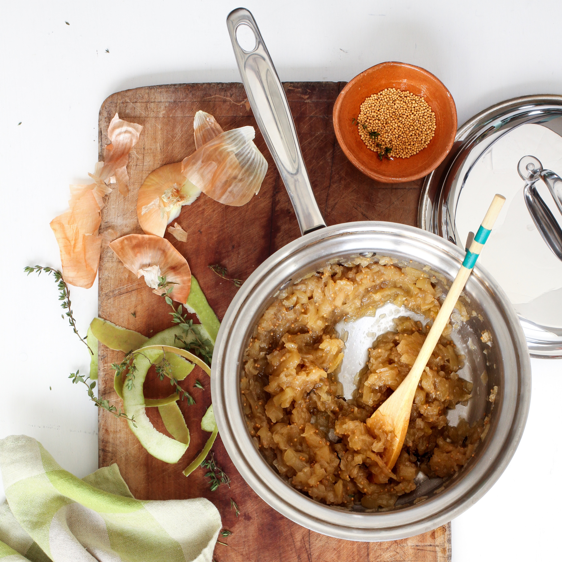 Cooking scene with a pot of food on a wooden cutting board.