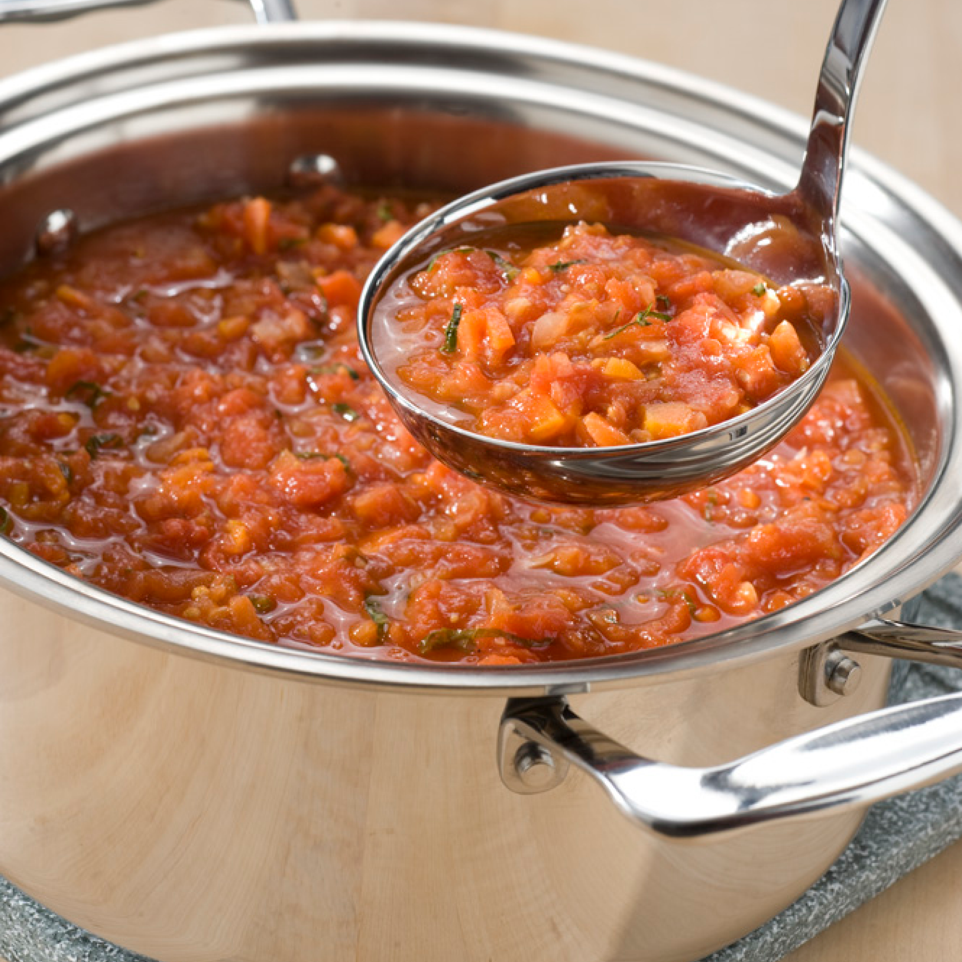 Stainless steel stockpot with tomato sauce and ladle