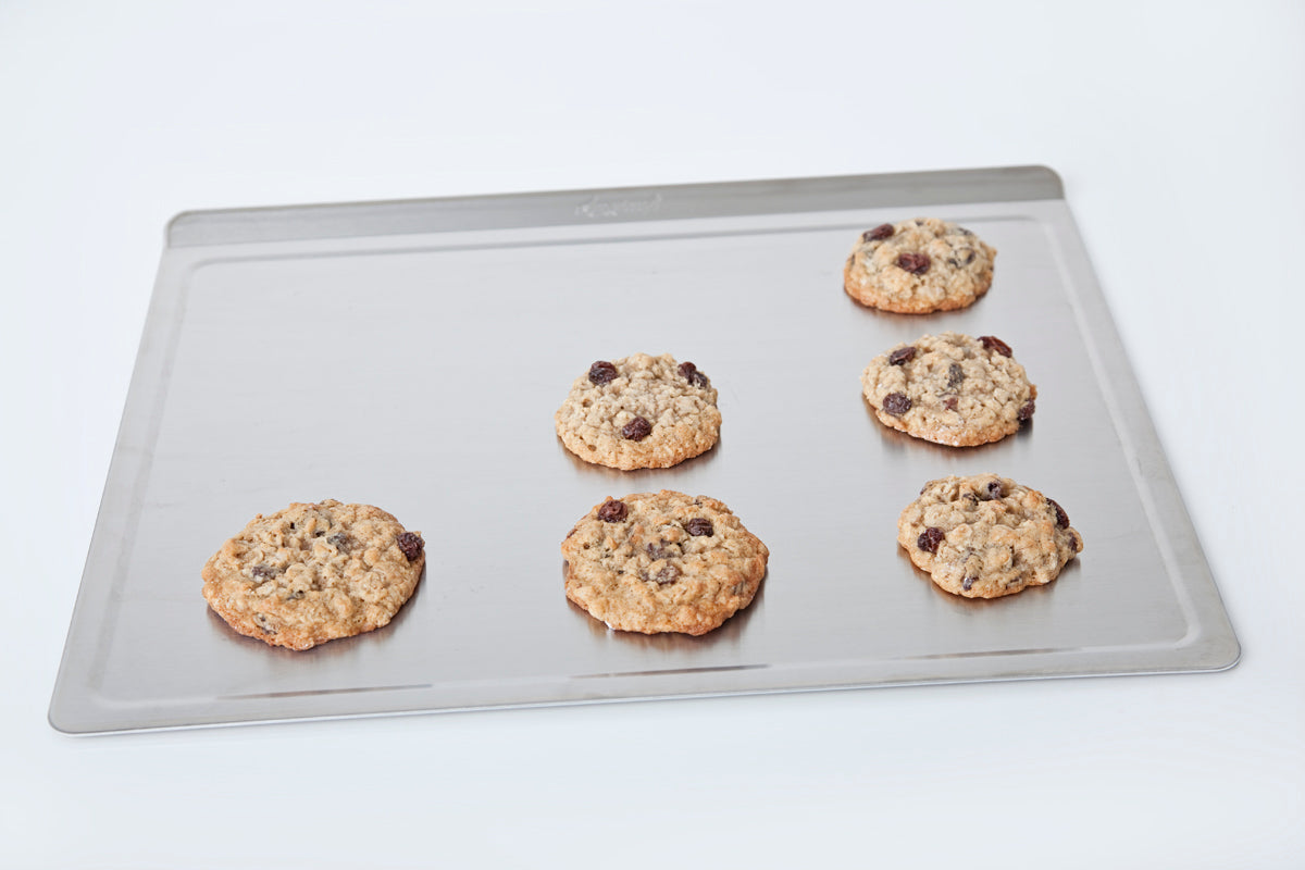 Large stainless steel cookie sheet with six baked cookies on it