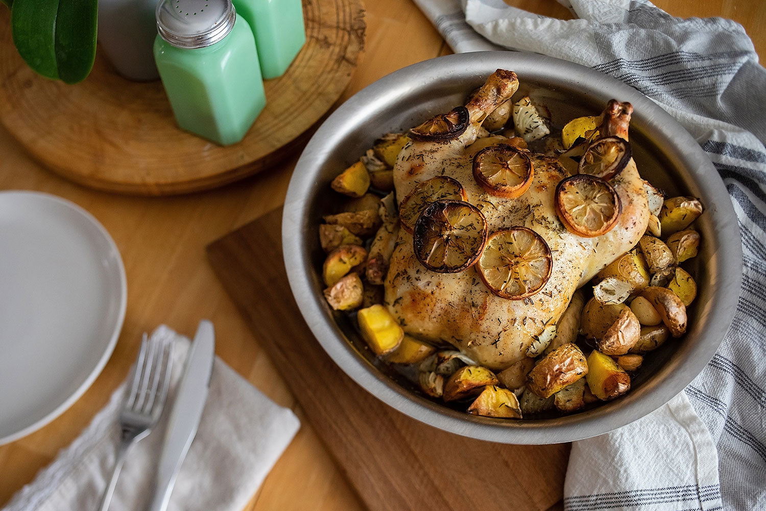 A 12-inch stainless steel pan with roasted chicken and vegetables, garnished with lemon slices.