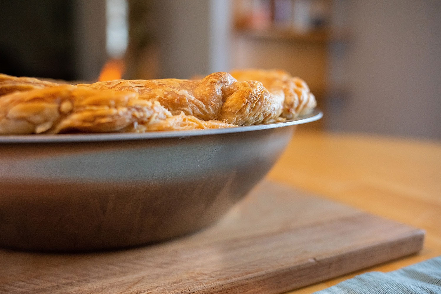 A close-up of a 12" stainless steel oven-to-table pan with a golden pastry on the edge.