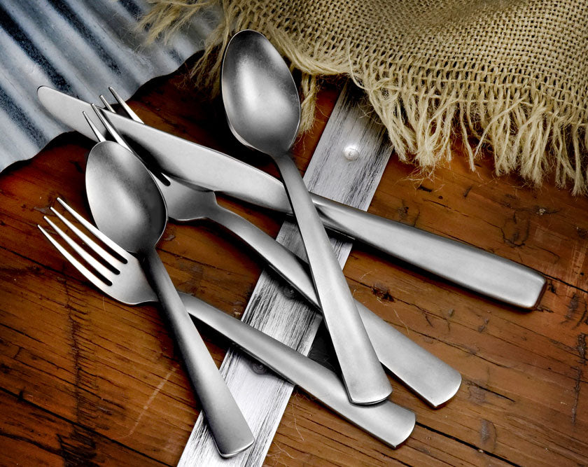 American Industrial 65 Piece Set including forks, knives, and spoons on a wooden surface