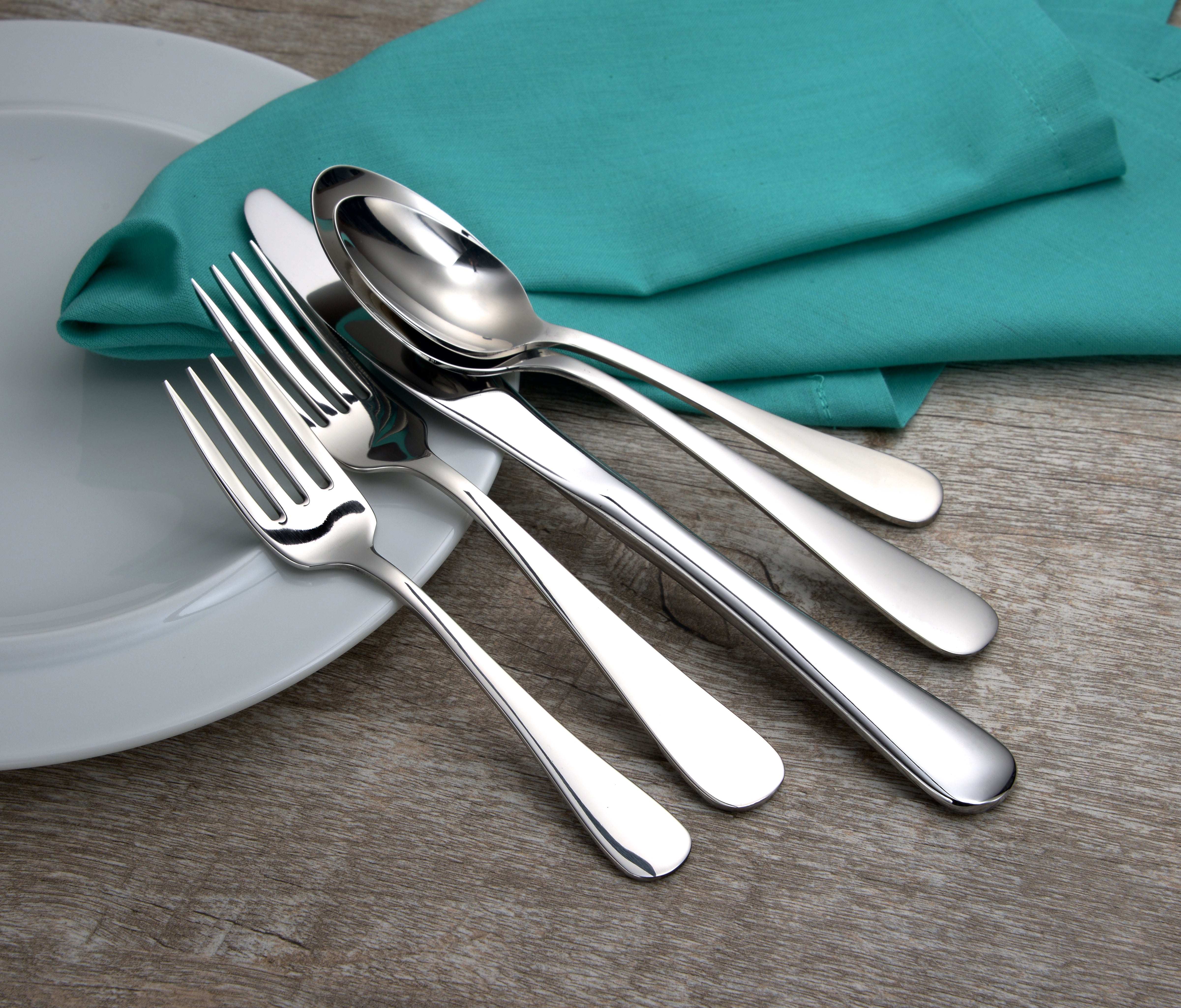 Annapolis 45 Piece Set flatware displayed on a wooden table with a plate and teal napkin
