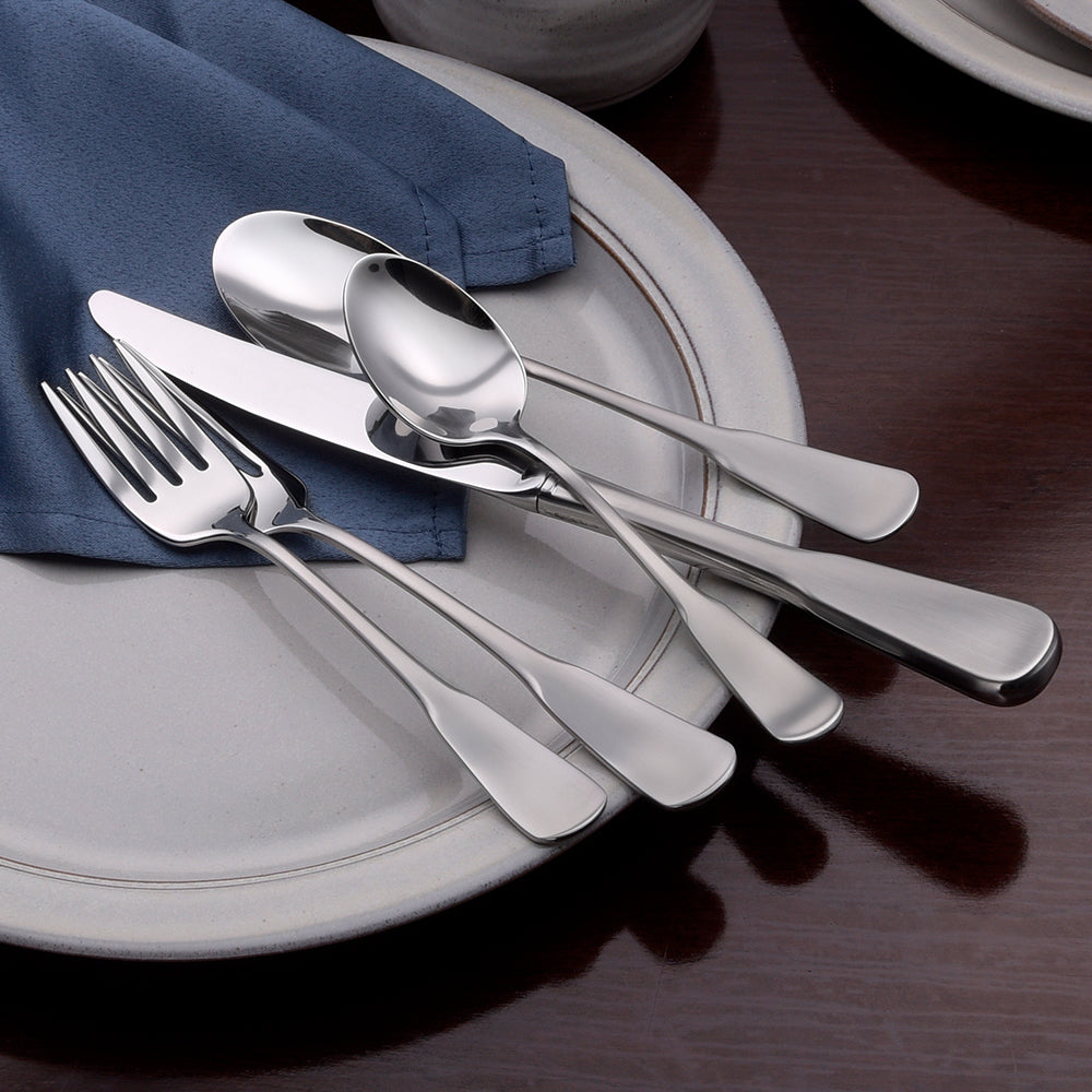 Candra 65 Piece Set flatware displayed on a plate with a blue napkin