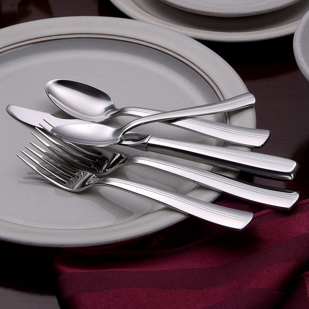 Cedarcrest 65 Piece Set flatware displayed on plates with a burgundy napkin