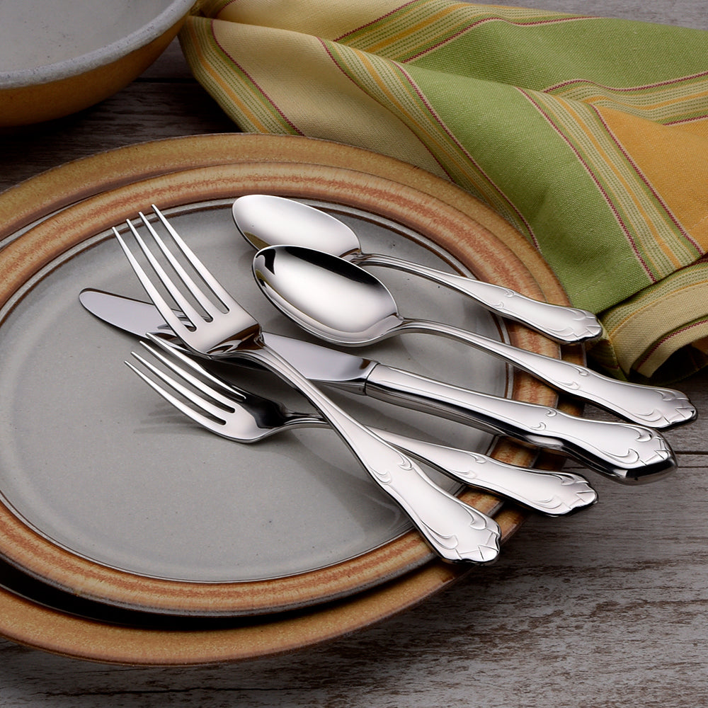 Champlin 65 Piece Set flatware displayed on plates with a napkin