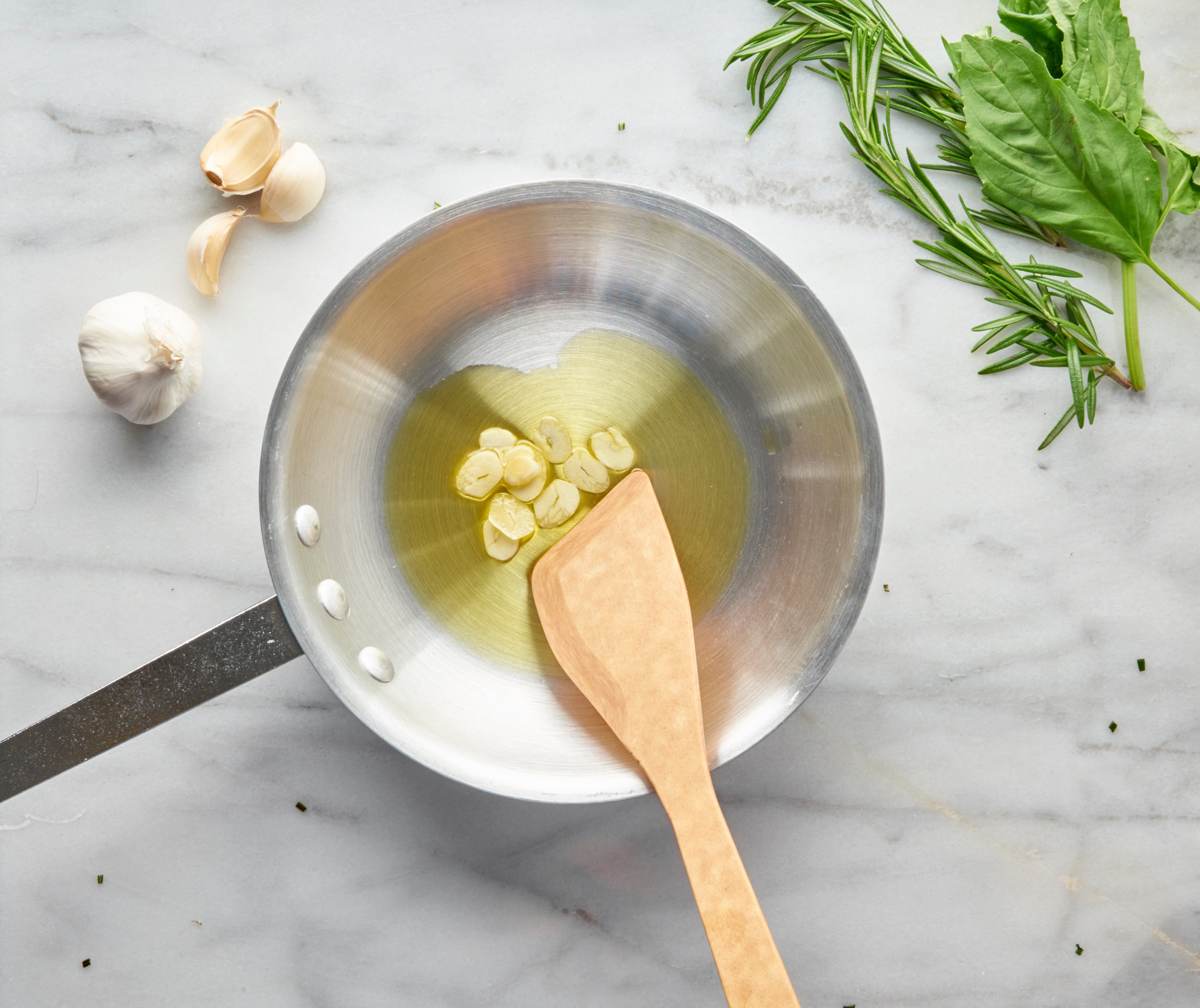 Natural sauté spoon in a pan with garlic and herbs