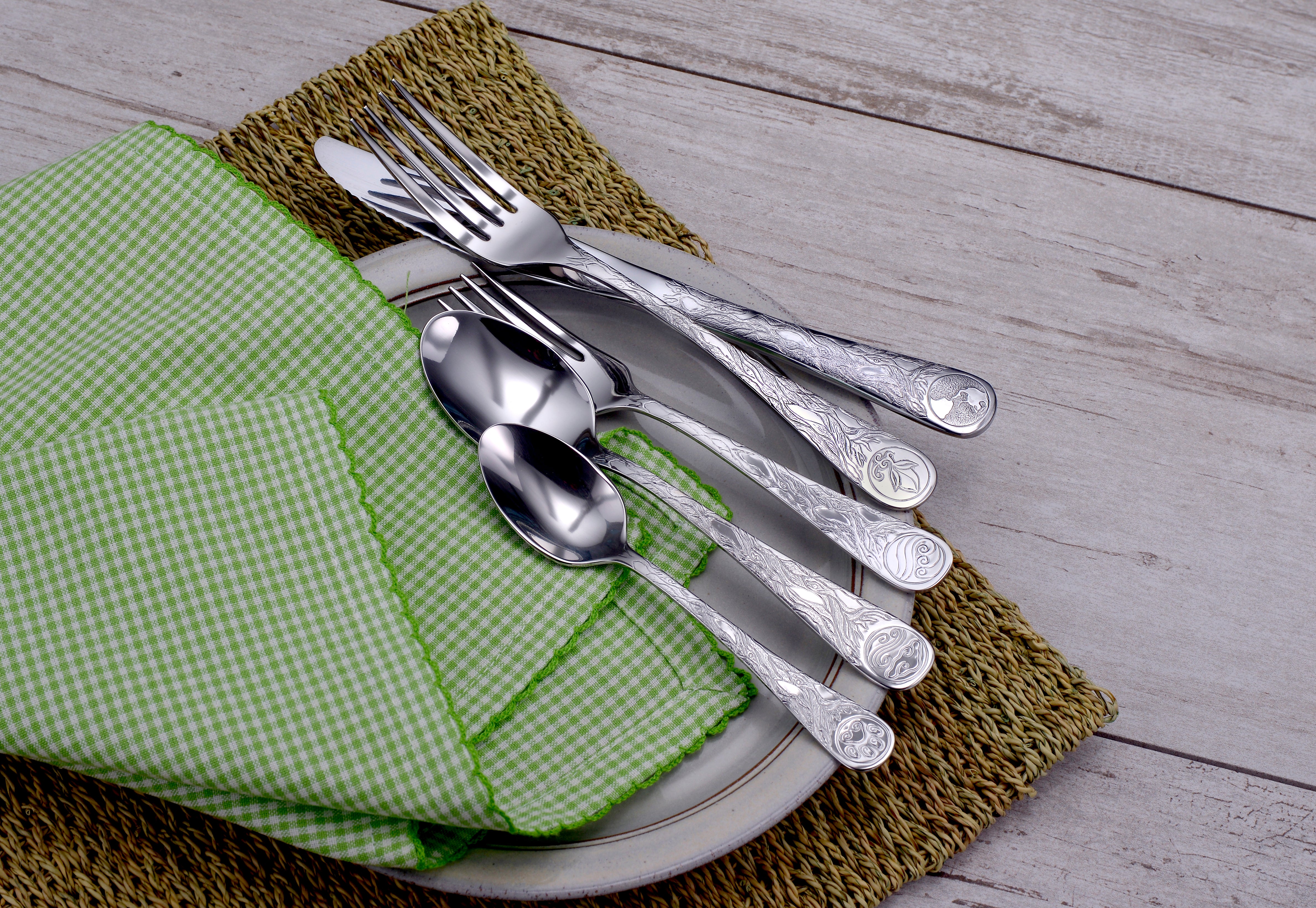 Earth Pattern Flatware set displayed on a plate with green checkered napkin and woven placemat.