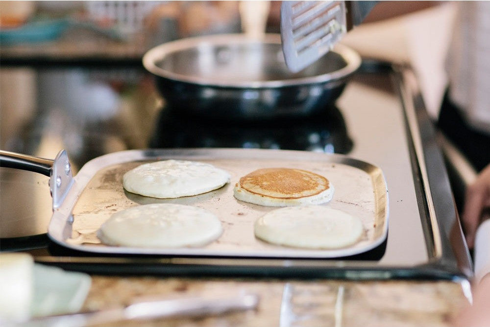 Cooking pancakes on the 11 Inch Square Griddle with a spatula.