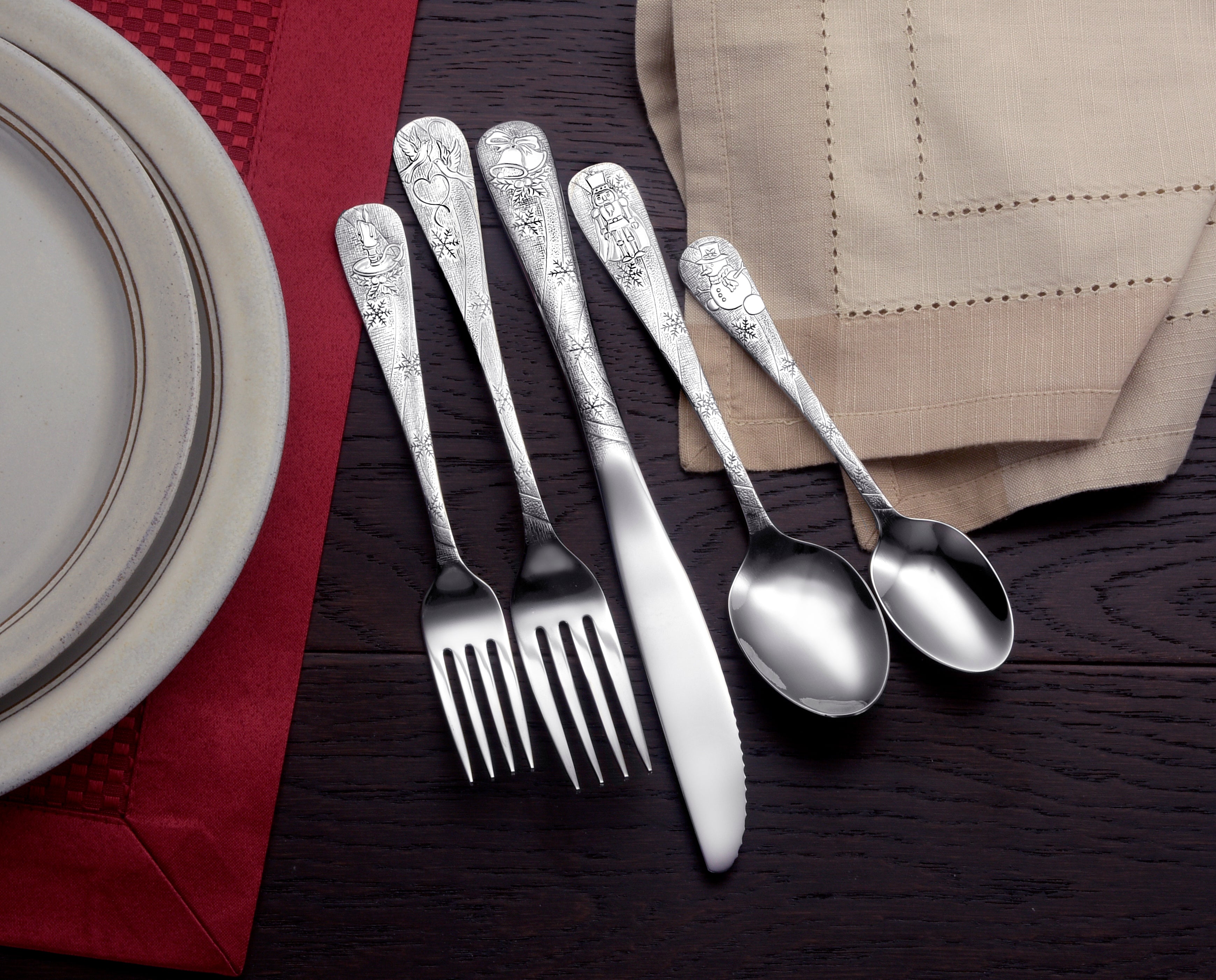 Five pieces of Holidays flatware set displayed on a table with a plate and napkin.