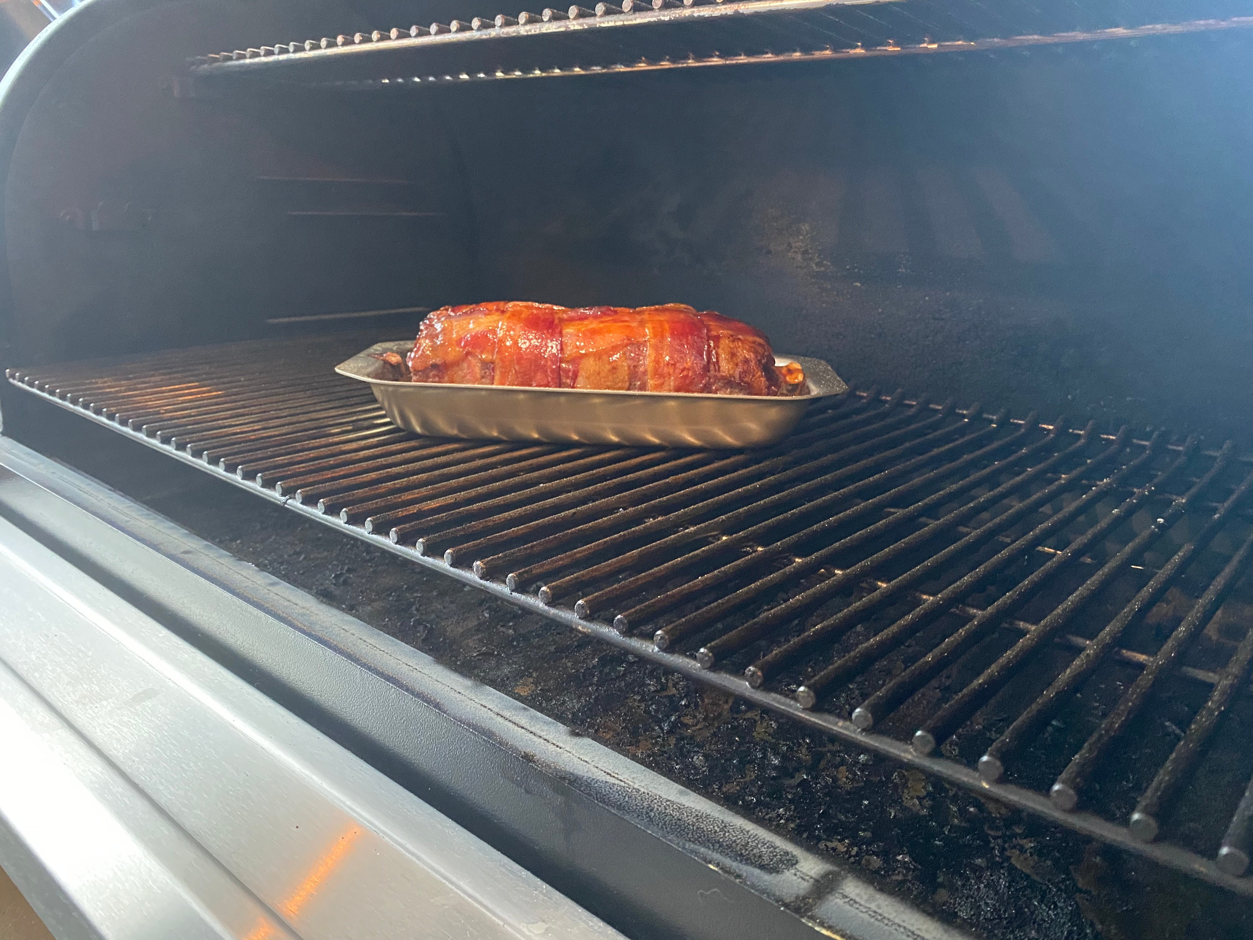 A stainless steel pan with meatloaf inside, placed in a grill.
