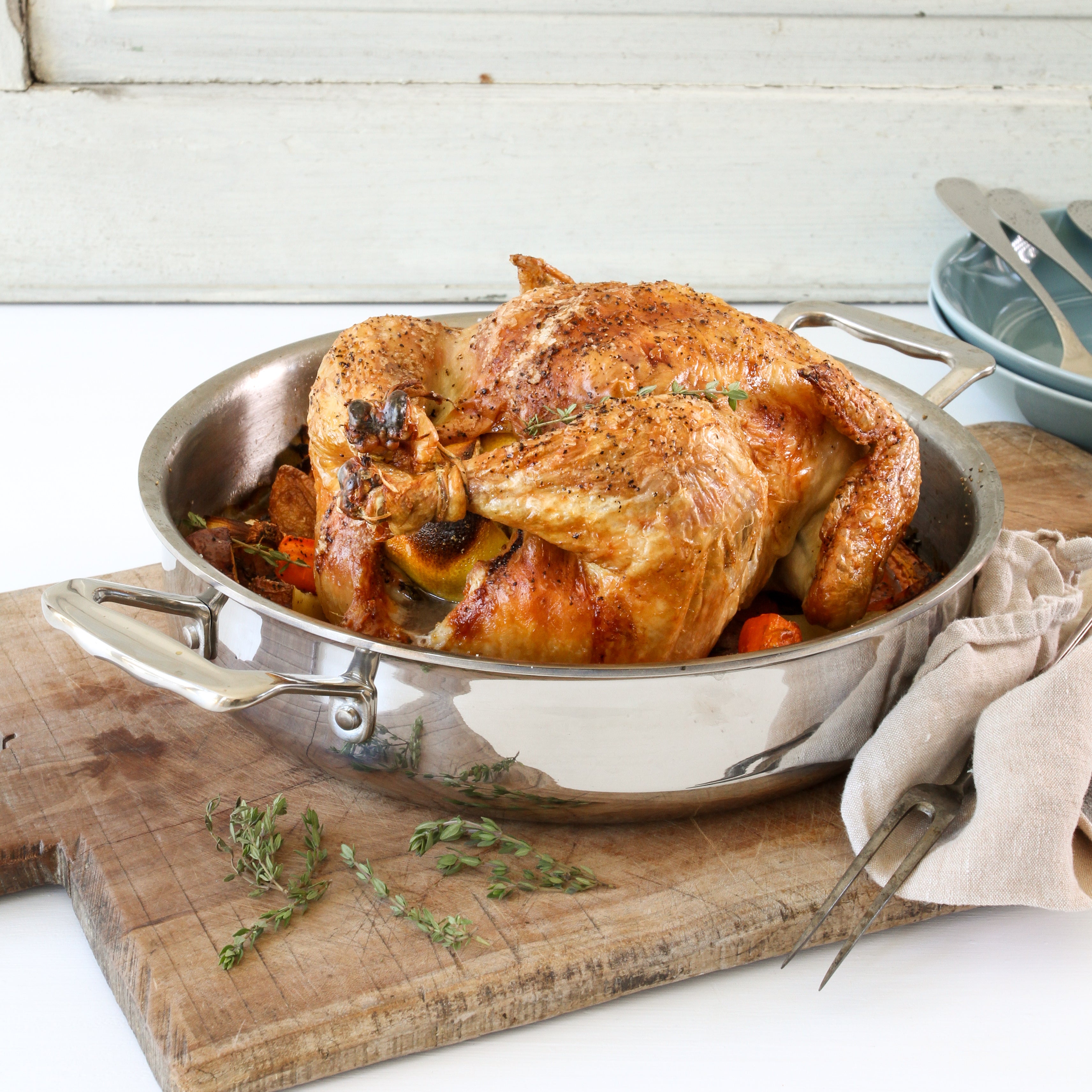A roasted chicken in a stainless steel 3-in-1 roasting pan with vegetables.