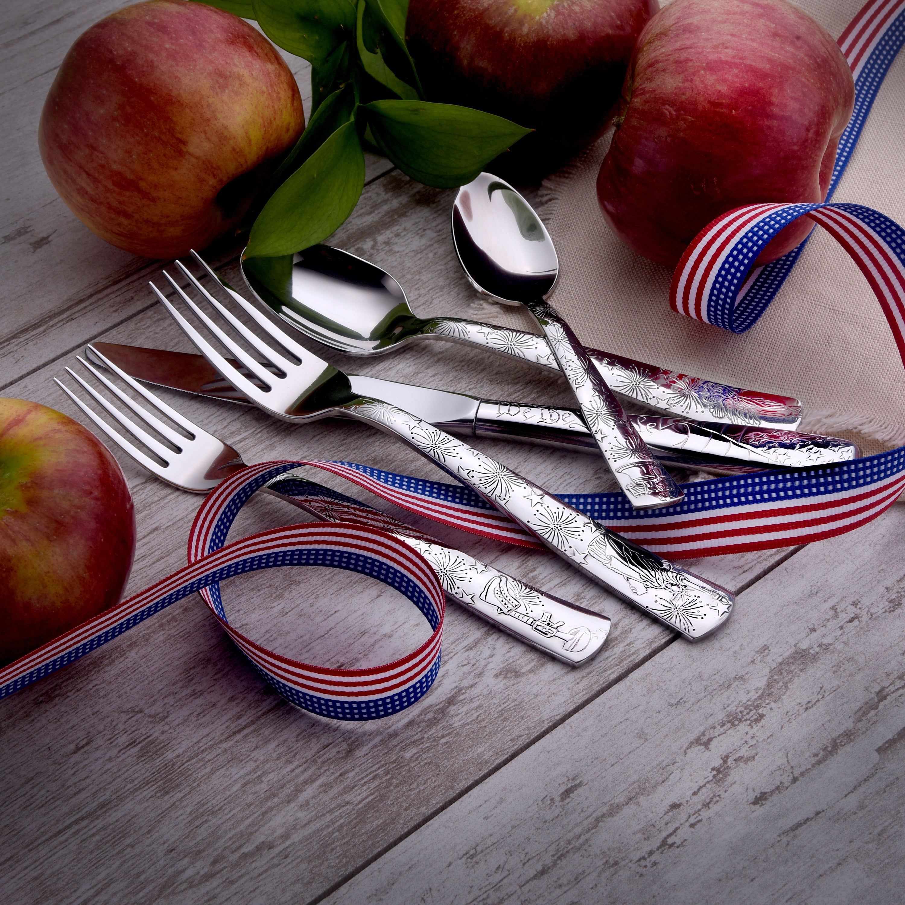 Liberty 45 Piece Set flatware displayed with apples and patriotic ribbon