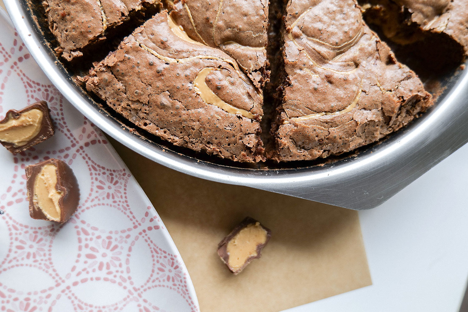 Close-up of a round brownie pan with brownies cut into slices and a piece of candy beside it.