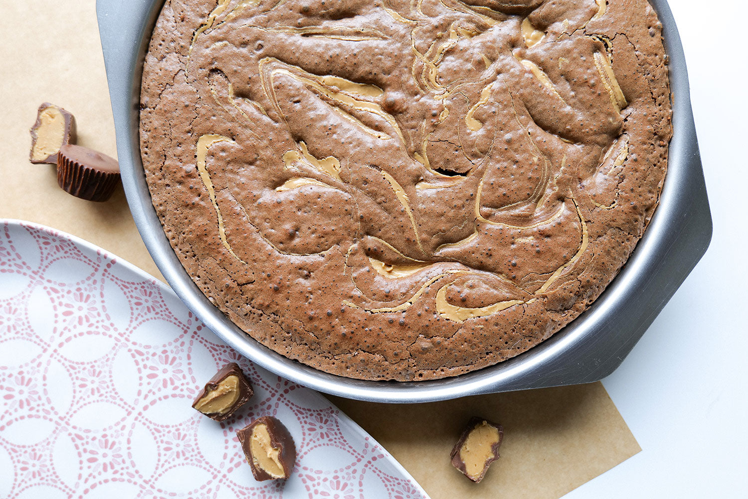 Freshly baked brownies in a 9-inch round stainless steel pan with peanut butter swirls