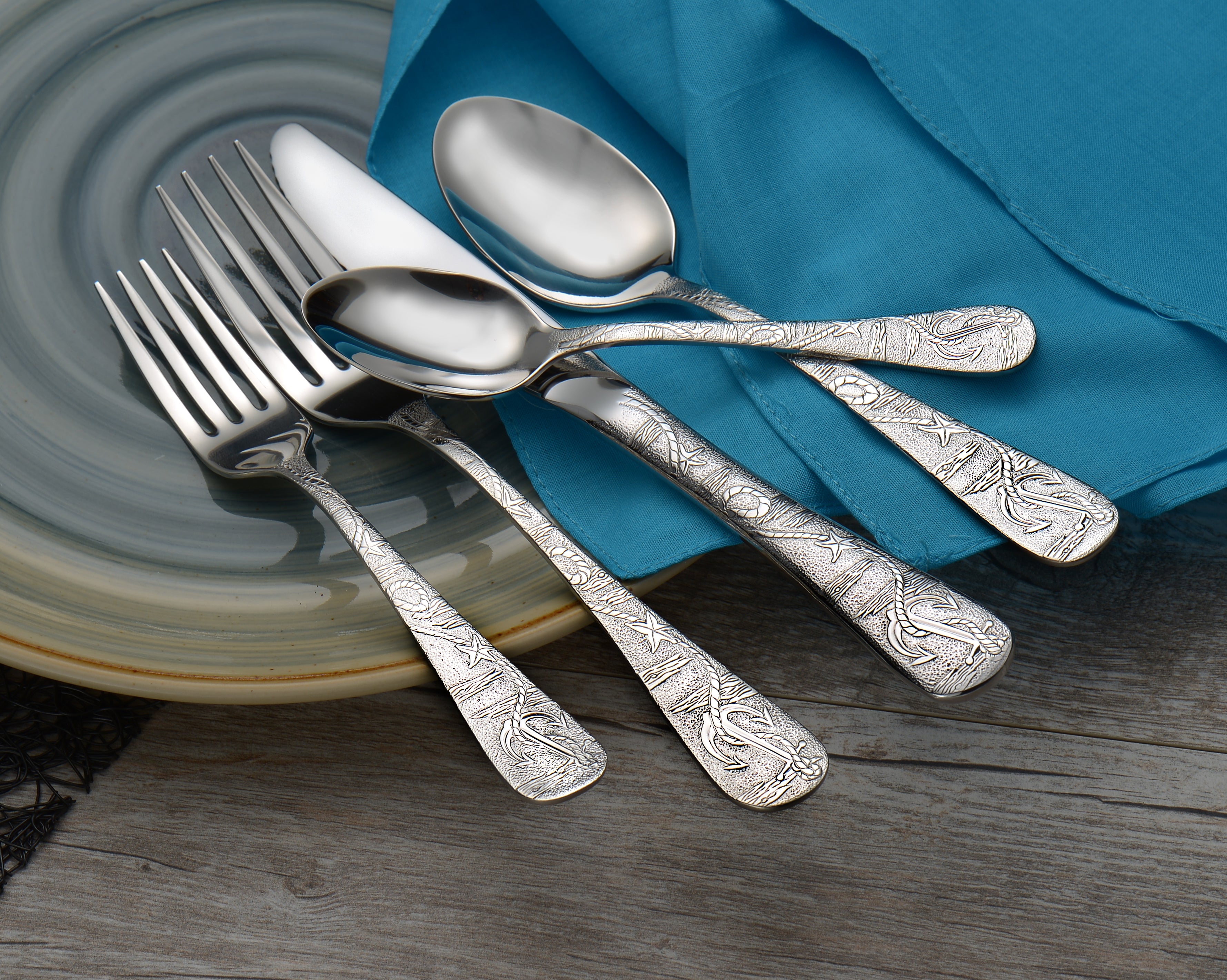Old Harbor 45 Piece Set featuring ornate silver utensils on a plate with a blue cloth