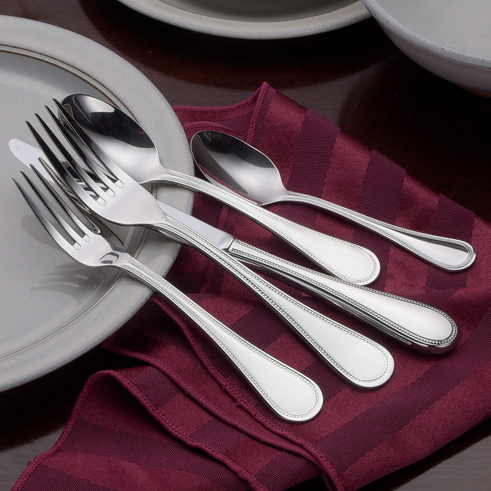 Set of stainless steel forks and spoons on a maroon cloth