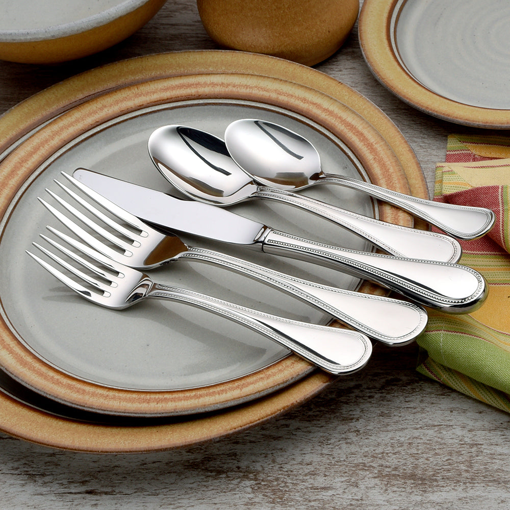 Set of stainless steel utensils including forks, knives, and spoons on plates
