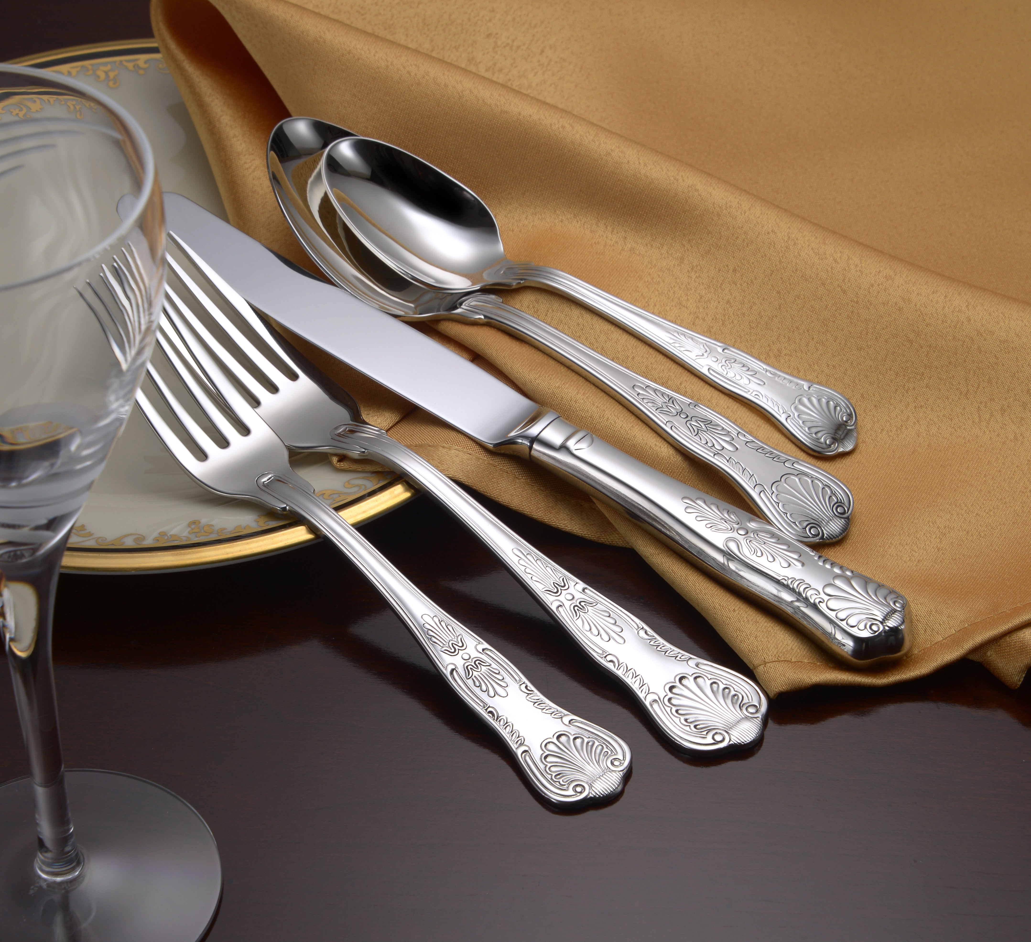 Sheffield 45 Piece Flatware Set displayed on a table with a gold cloth and plate