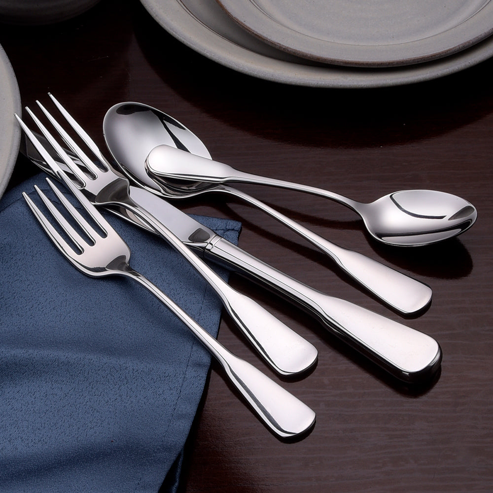 A set of polished stainless steel forks, spoons, and knives arranged on a table with a blue napkin.