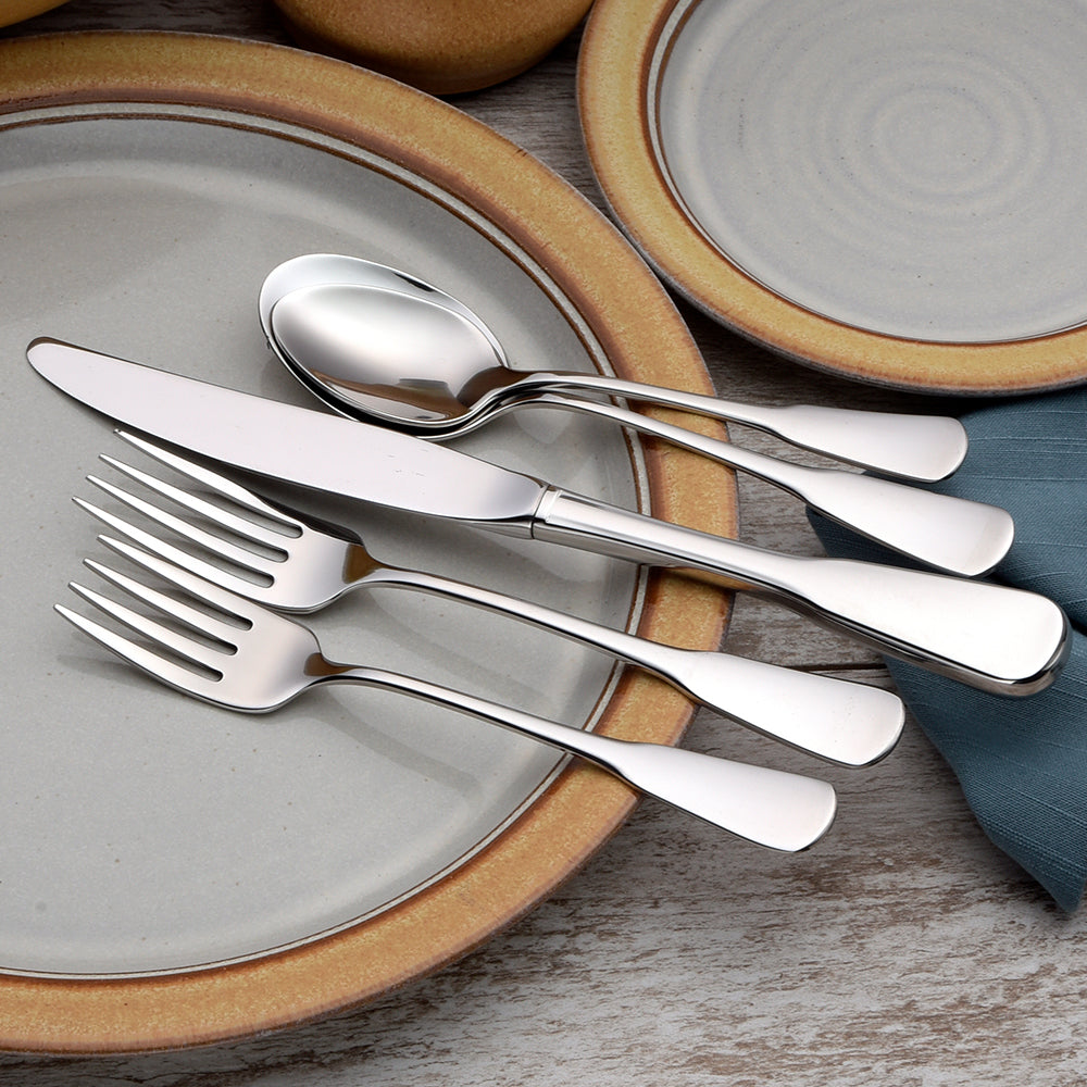 Four pieces of Susanna flatware including a knife, spoon, and two forks on a plate.