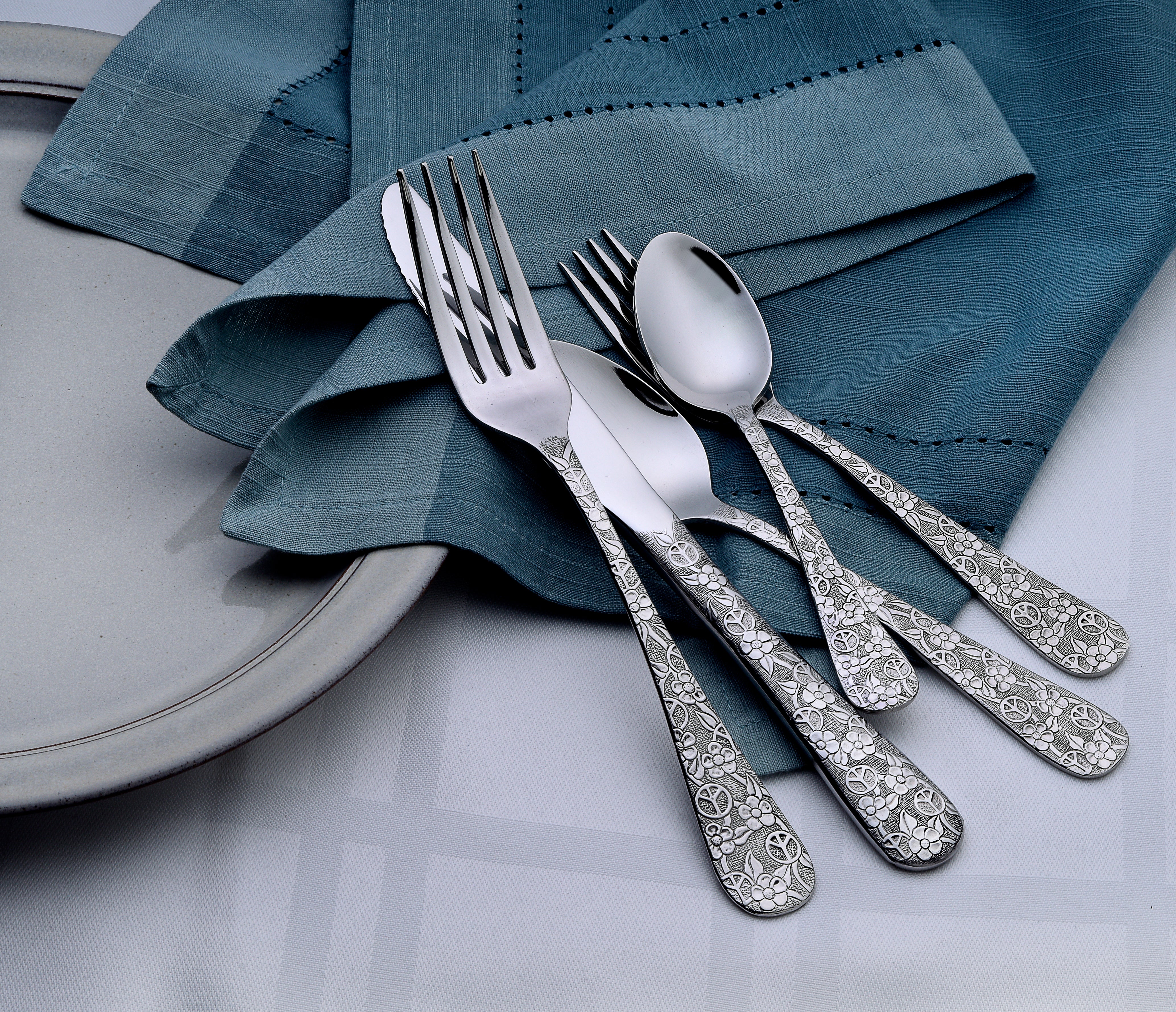 Woodstock 45 Piece Flatware Set with peace and flower designs on a table setting