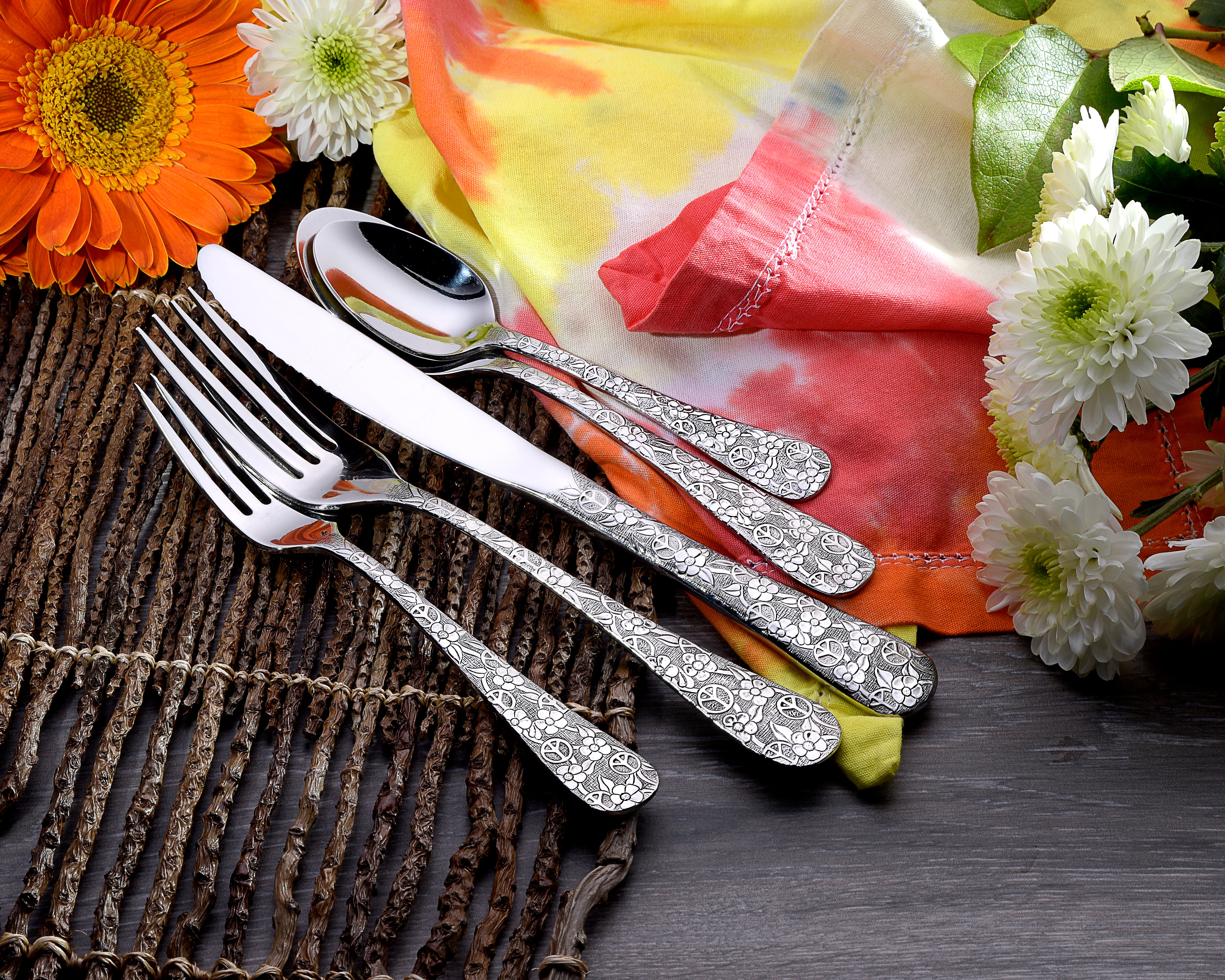 Woodstock 45 Piece Flatware Set with floral design on handles, displayed with flowers and a colorful cloth