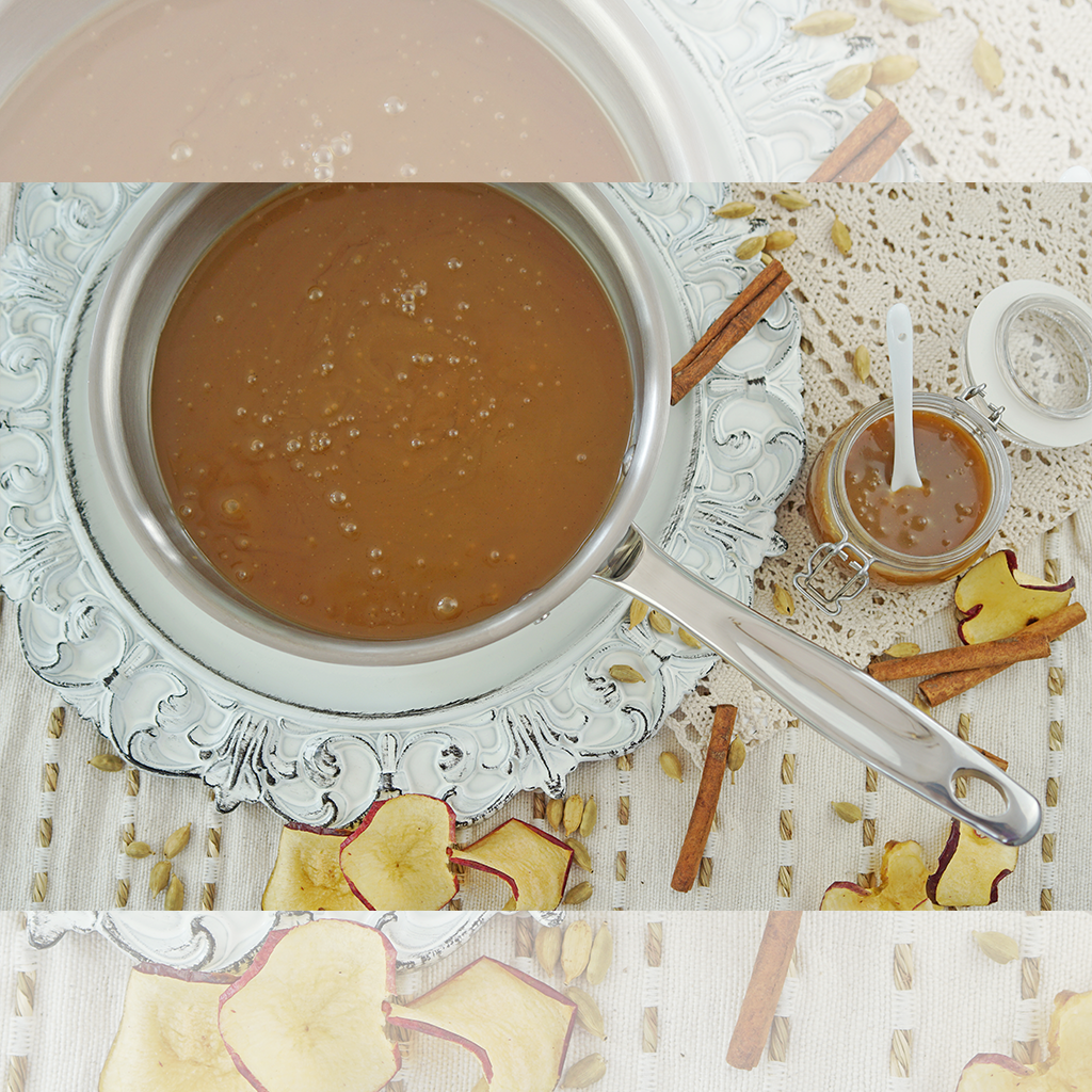 A 2-quart stainless steel saucier with caramel sauce, cinnamon sticks, and dried apple slices.